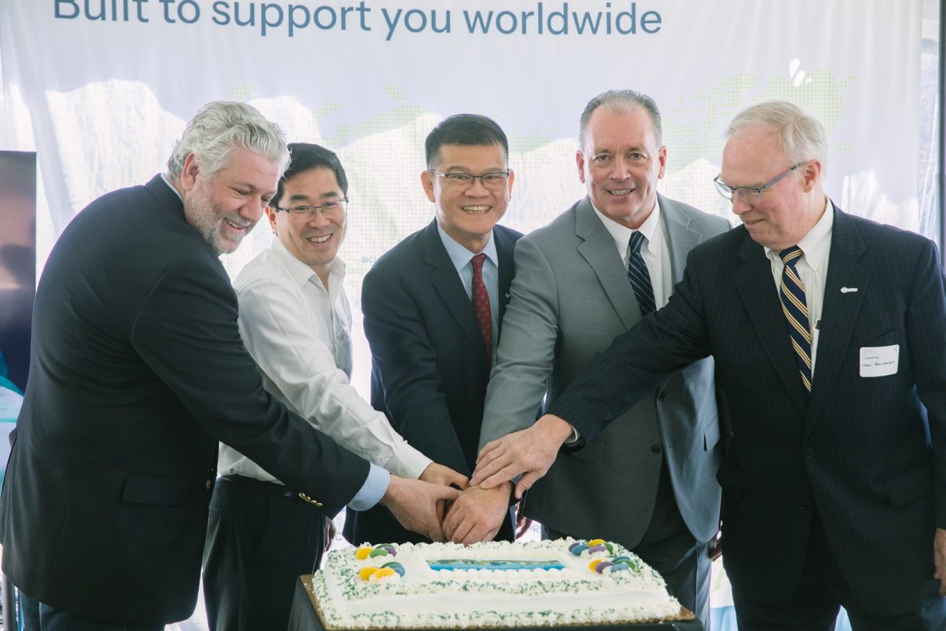 ChemPartner leaders and guests cutting the Boston Center of Excellence first-anniversary cake